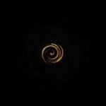 Elegant golden spiral design on a dark black background representing precision and balance